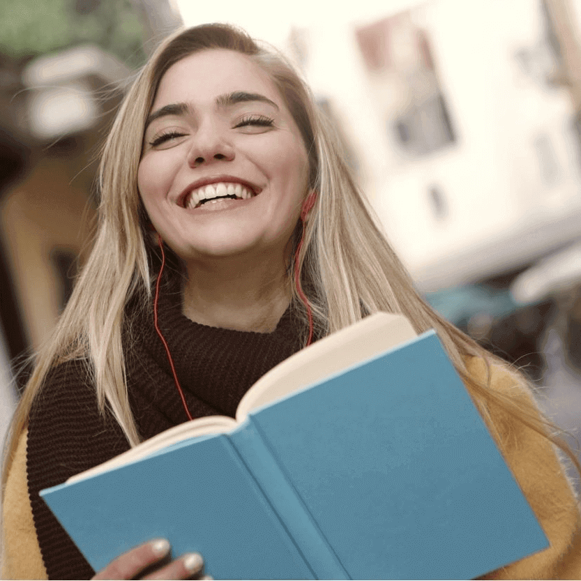 Smiling girl with earphones and books